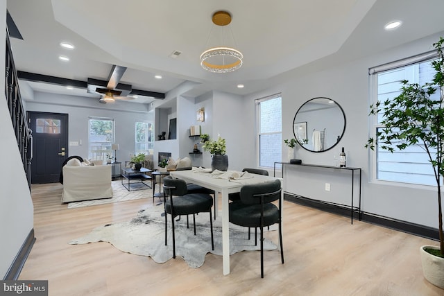 dining room featuring beamed ceiling, coffered ceiling, a wealth of natural light, and light wood-type flooring