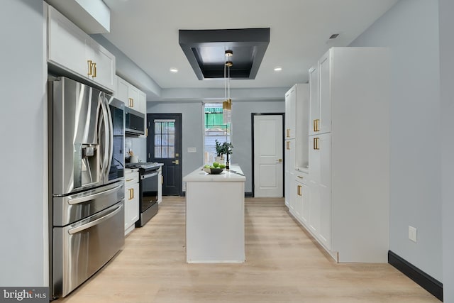 kitchen featuring a kitchen island, white cabinets, a tray ceiling, stainless steel appliances, and light wood-type flooring