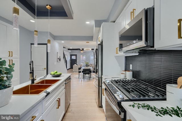 kitchen with pendant lighting, white cabinetry, stainless steel appliances, and sink