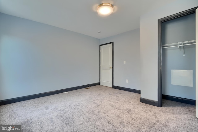 unfurnished bedroom with light colored carpet and a closet