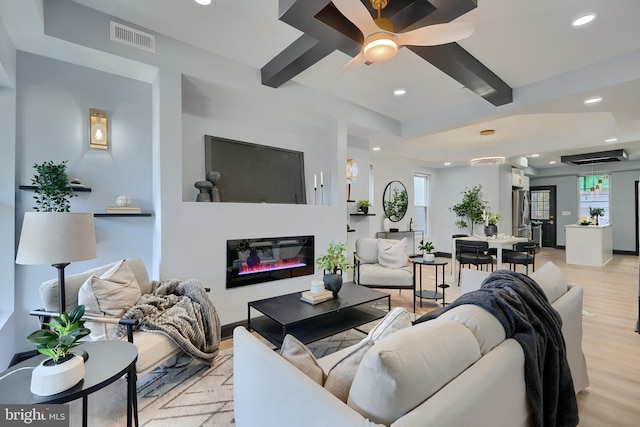 living room featuring ceiling fan, plenty of natural light, beam ceiling, and light wood-type flooring