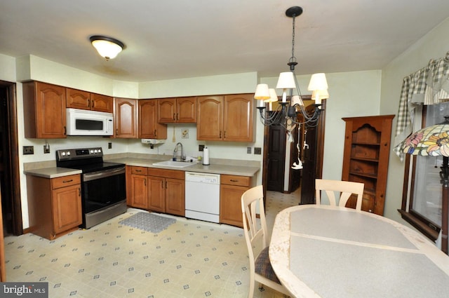 kitchen featuring sink, white appliances, decorative light fixtures, and a chandelier