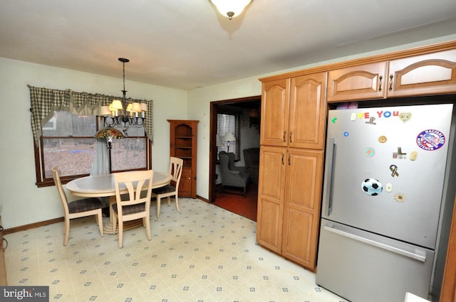 kitchen with pendant lighting, a notable chandelier, and stainless steel fridge