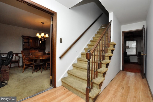 staircase featuring hardwood / wood-style flooring and a chandelier