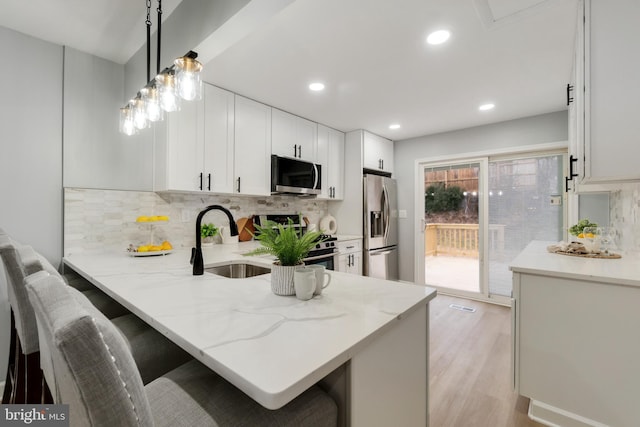 kitchen with stainless steel appliances, decorative light fixtures, a breakfast bar, and kitchen peninsula