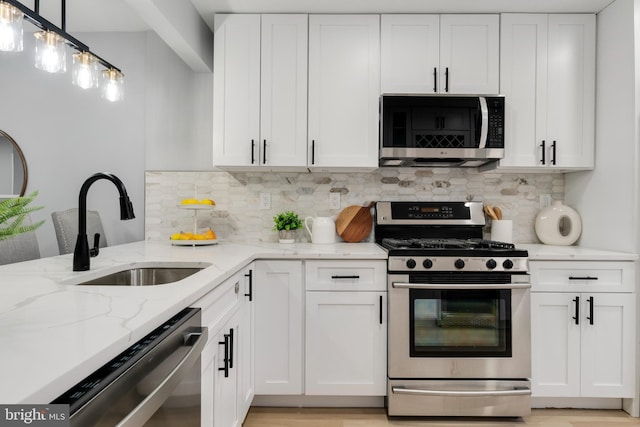 kitchen featuring white cabinetry, appliances with stainless steel finishes, sink, and pendant lighting