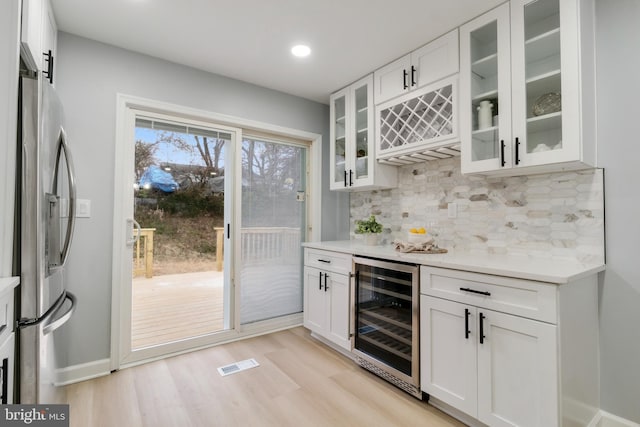 bar featuring wine cooler, white cabinets, backsplash, and stainless steel refrigerator with ice dispenser