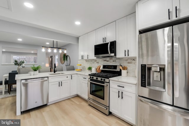 kitchen featuring white cabinetry, stainless steel appliances, kitchen peninsula, and sink