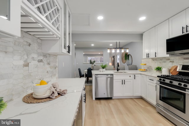 kitchen with sink, decorative light fixtures, white cabinets, and appliances with stainless steel finishes