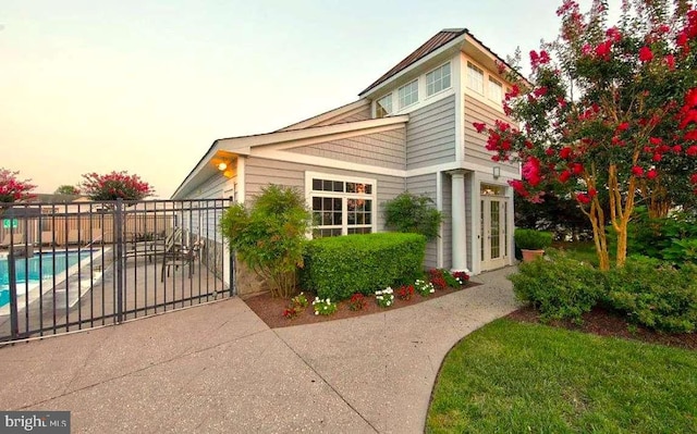 property exterior at dusk featuring a fenced in pool and a patio area