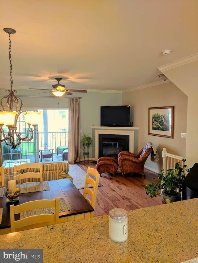 dining space featuring wood-type flooring, ceiling fan with notable chandelier, and crown molding