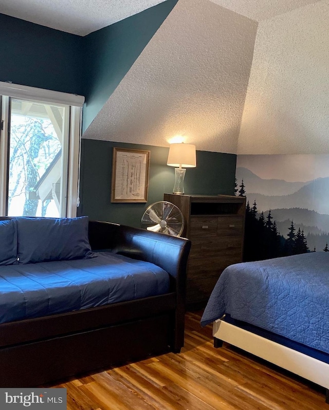 bedroom featuring wood-type flooring, vaulted ceiling, and a textured ceiling