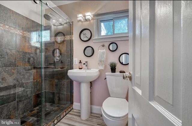 bathroom with a shower with shower door, sink, and toilet