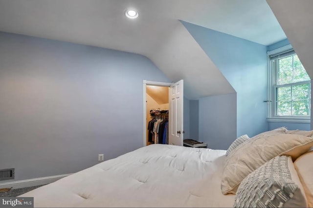 bedroom featuring a walk in closet, lofted ceiling, and a closet