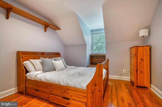 bedroom featuring vaulted ceiling with beams and dark hardwood / wood-style floors