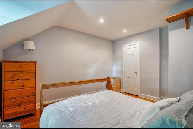 bedroom with wood-type flooring and vaulted ceiling