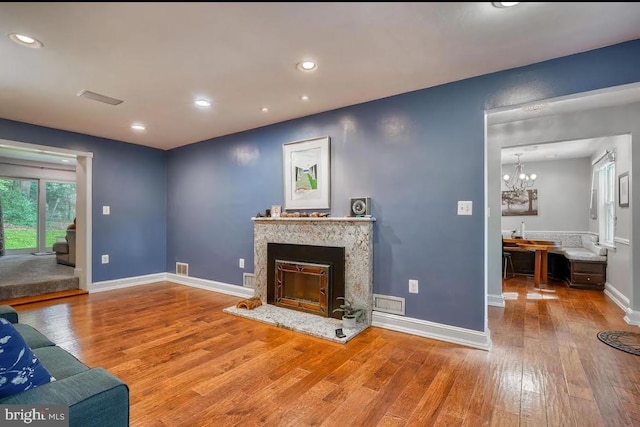 living room featuring a chandelier, hardwood / wood-style floors, and a fireplace