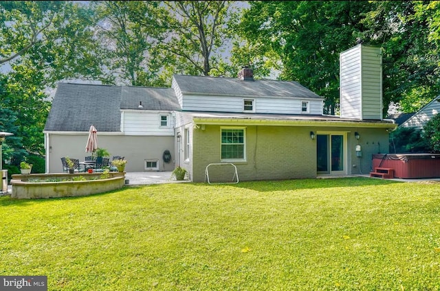 rear view of house with a yard, a hot tub, and a patio area