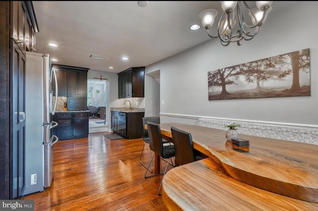 dining room with a notable chandelier, hardwood / wood-style flooring, and sink