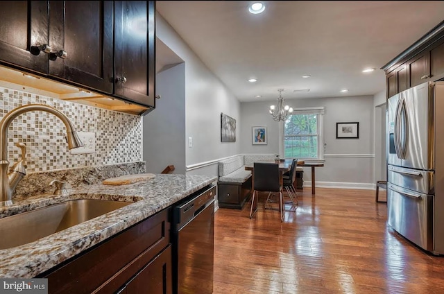 kitchen featuring sink, light stone counters, stainless steel fridge with ice dispenser, dark brown cabinets, and dishwasher