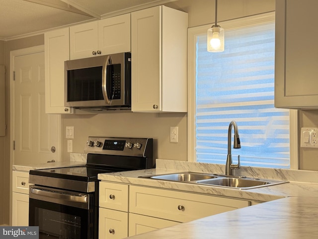 kitchen with appliances with stainless steel finishes, sink, white cabinets, and decorative light fixtures