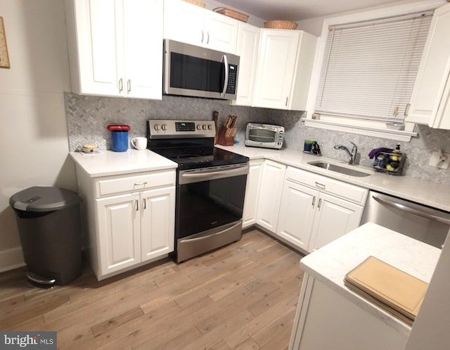 kitchen featuring tasteful backsplash, sink, white cabinets, and appliances with stainless steel finishes