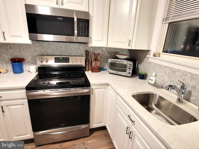 kitchen with stainless steel appliances, white cabinetry, and sink