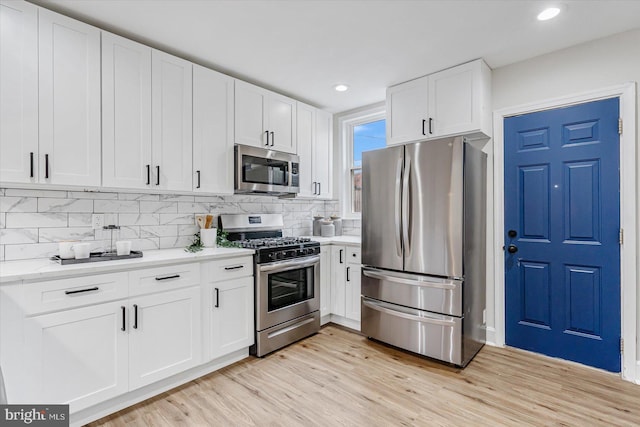 kitchen featuring tasteful backsplash, light hardwood / wood-style flooring, white cabinets, and appliances with stainless steel finishes