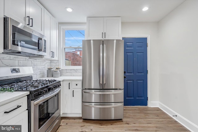 kitchen featuring decorative backsplash, light hardwood / wood-style floors, white cabinets, and appliances with stainless steel finishes