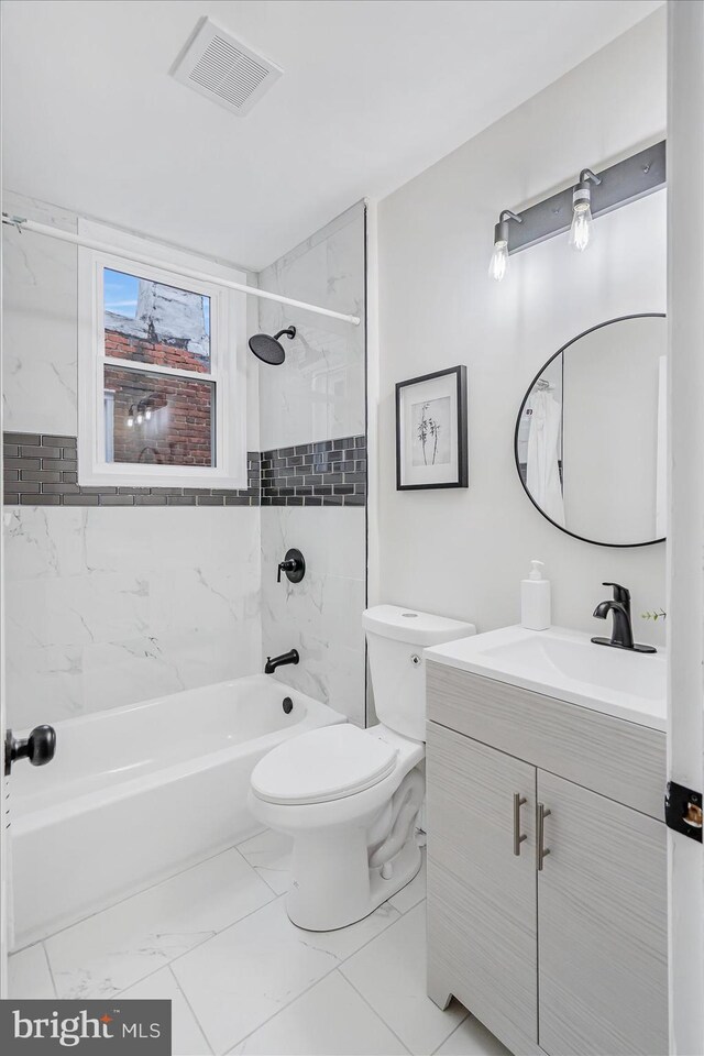 full bathroom featuring vanity, tiled shower / bath combo, and toilet