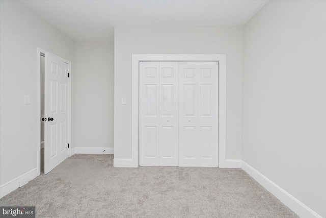 unfurnished bedroom featuring light carpet and a closet