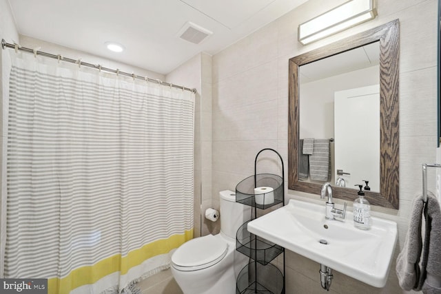 bathroom featuring sink, tile walls, curtained shower, and toilet