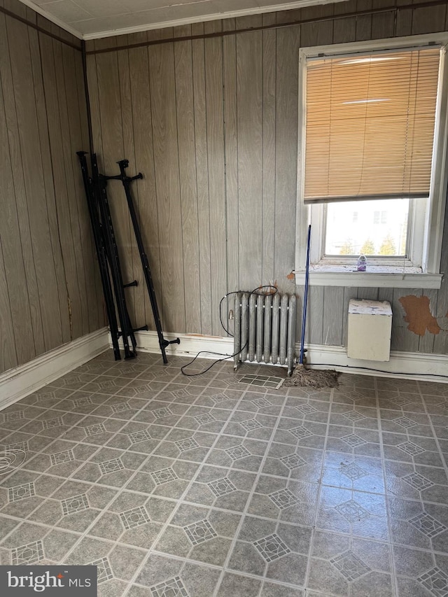 spare room featuring radiator heating unit and wooden walls