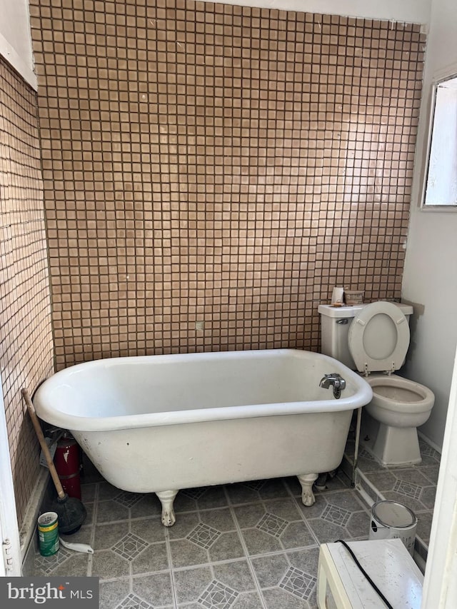 bathroom featuring tile walls, a bathtub, tile patterned floors, and toilet