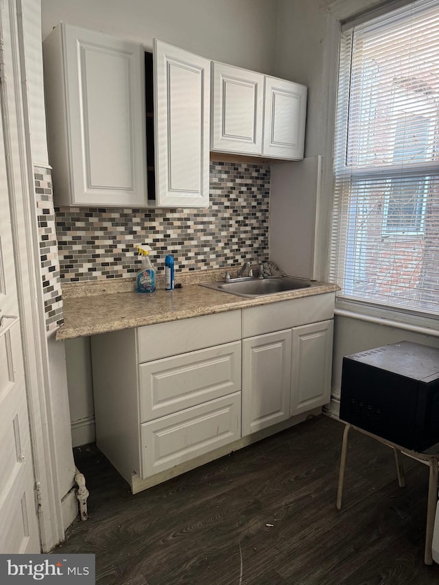 kitchen featuring dark wood-type flooring, sink, white cabinets, and backsplash