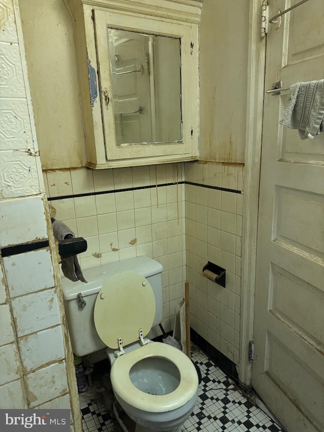 bathroom with toilet and tile walls