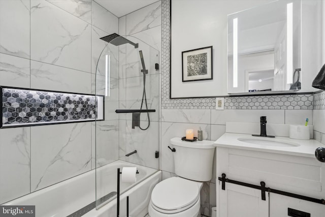 full bathroom with tiled shower / bath combo, toilet, tile walls, and vanity