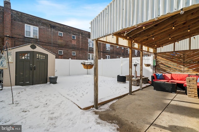 snow covered patio with outdoor lounge area and a storage unit