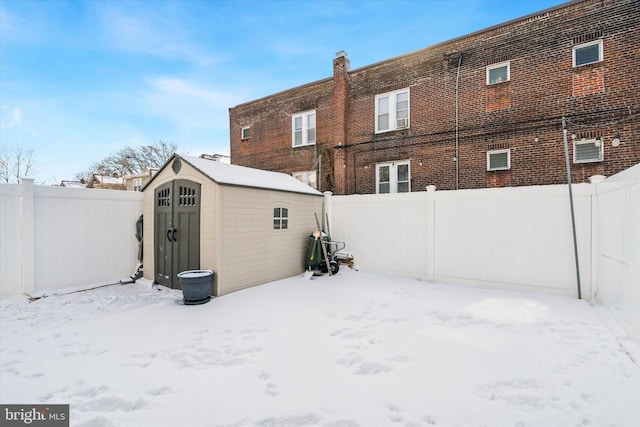 snow covered back of property featuring a shed