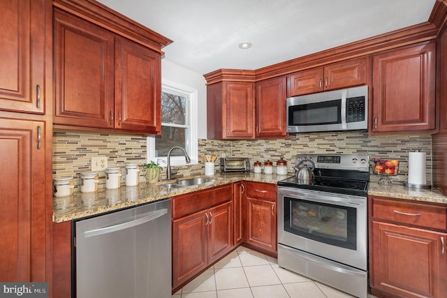 kitchen featuring stainless steel appliances, light stone counters, light tile patterned flooring, and a sink