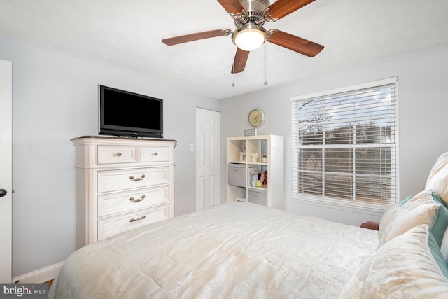 bedroom with baseboards, a ceiling fan, and a textured ceiling