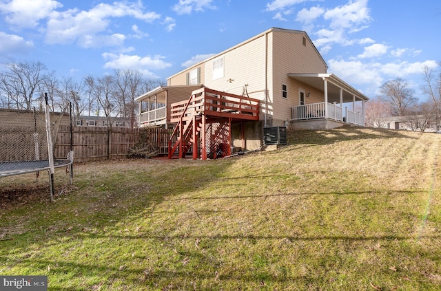 back of house with a deck, central AC unit, stairway, a lawn, and a trampoline