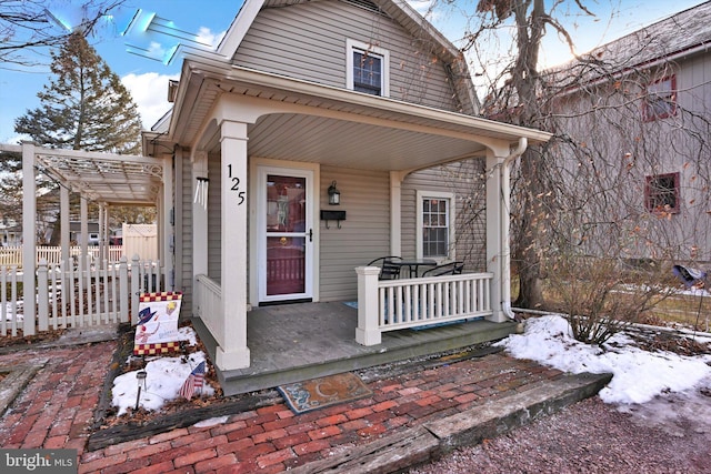 snow covered property entrance with a porch