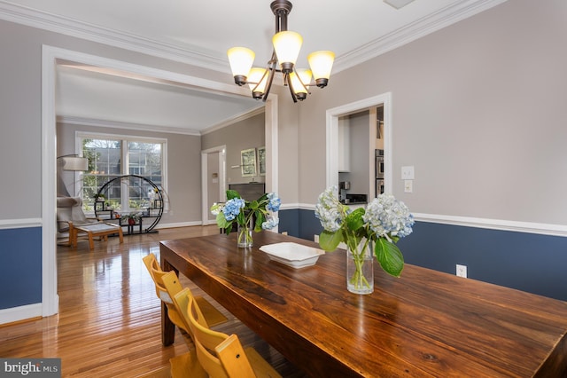 dining space featuring an inviting chandelier, ornamental molding, and hardwood / wood-style floors