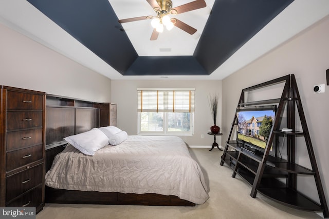 bedroom featuring light carpet, a tray ceiling, and ceiling fan