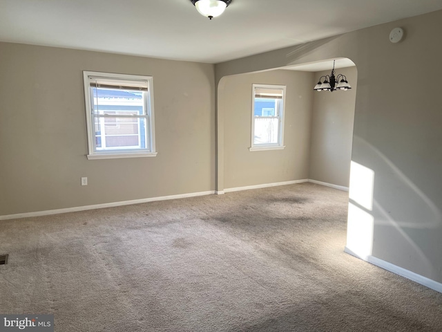 carpeted empty room with plenty of natural light and a notable chandelier