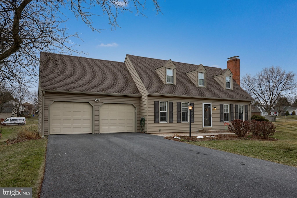 new england style home featuring a garage and a front lawn