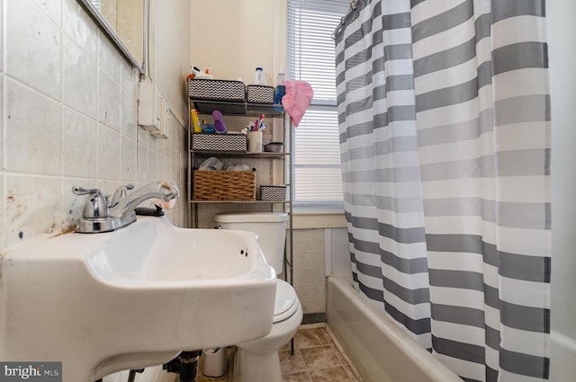 full bathroom with shower / bath combo with shower curtain, tile patterned flooring, a sink, and tile walls