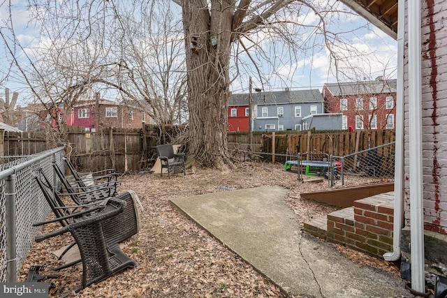 view of yard featuring a patio area, a trampoline, a fenced backyard, and a residential view