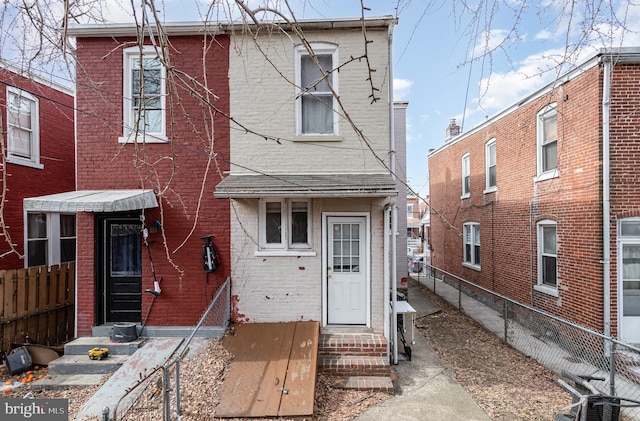 view of front of property with entry steps, fence, and brick siding